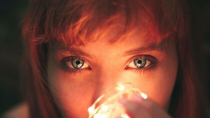 A woman holding a lightbulb to her face expressing her desire for the light