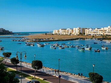 Traditional boats along the Bouregreg Marina with sleek modern buildings rising behind them, symbolising Morocco’s fusion of past and present