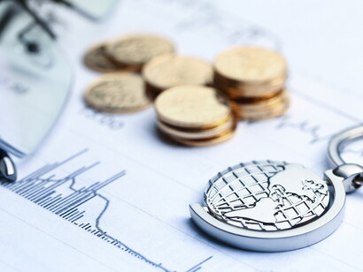 Monete, cartamoneta e mappamondo su sfondo bianco con grafici statistici: "Trump è arrivato a sostenere improbabili percentuali che gli altri Paesi, secondo lui e il suo staff, avrebbero imposto agli Stati Uniti"