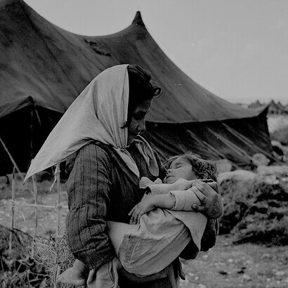 A Palestine refugee girl carries her sleeping baby sister in the newly formed Mia Mia camp, near the ancient port of Sidon, Lebanon