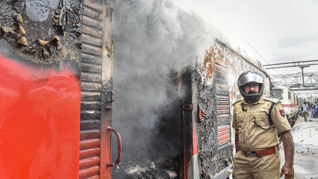 An Indian police officer standing by a train vandalised during Agniveer protests in Bihar