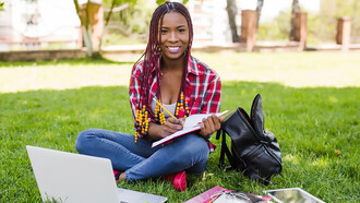 International student studying outdoors, posing in a scenic park