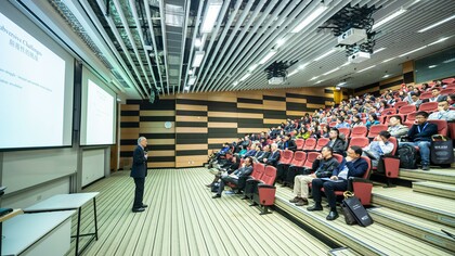 A man conducting his presentation and exercising his public speaking skills in an auditorium filled with people