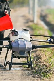 Individual refilling a big agricultural drone for farming use