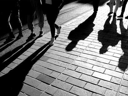 Silhouettes of people walking along the sidewalk in the evening light