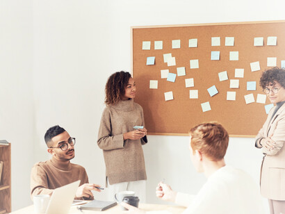 A female member of a digital marketing group strategizes together, while she goes over the notes on the board