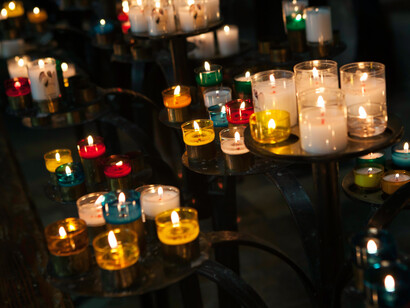 Different colored candles lit on trays