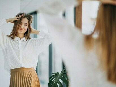 A woman looking into the mirror with confidence, representing a healthy and affirming self-view