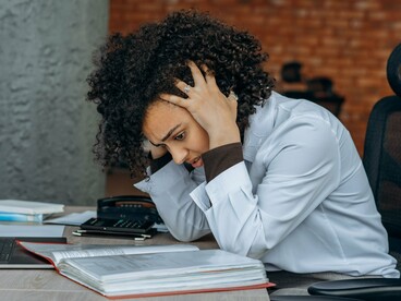 A woman coping with mounting stress at her desk, reflecting the connection between mental strain and the nervous system