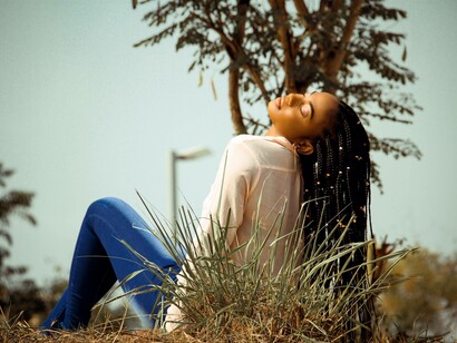 A woman laying down and soaking in the sun with her black hairstyle caressing her back