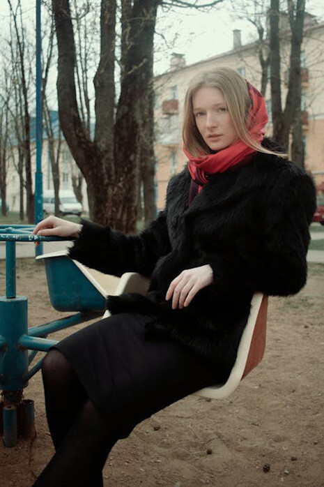A woman in a black fur coat carries a loaf of bread through the streets of a Soviet city in Russia