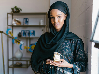 A woman in a black hijab is holding a gift box