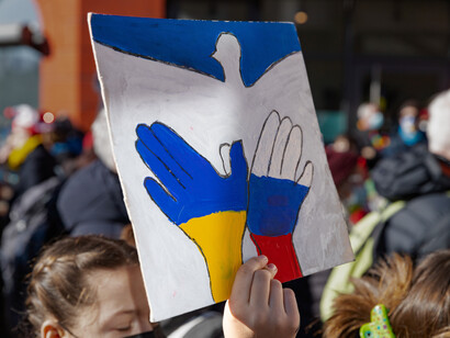 A protest sign in Cologne, Germany, depicts a white dove alongside the flags of Russia and Ukraine, symbolizing calls for peace amid the ongoing conflict