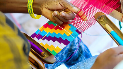 In the vibrant setting of Ghana in 2019, a shuttle skillfully maneuvers through the threads, contributing to the intricate artistry of Kente weaving, this snapshot captures the craftsmanship and tradition embedded in the process, where the shuttle becomes a symbol of the meticulous workmanship that brings the renowned Kente cloth to life