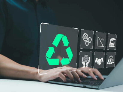 A person typing on a laptop with icons representing the circular economy, sustainability, recycling, and eco-friendly business practices, illustrating the integration of environmental and economic goals