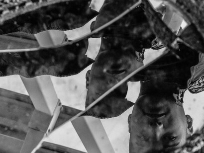 A man’s reflection fragmented across a broken mirror, representing the erosion of trust and the fractured reality surrounding political leadership