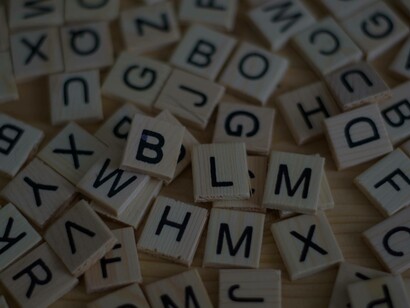 Tiles of letters scattered on the table not forming any words but if viewed closely they do map out a powerful meaning that of "BLM"
