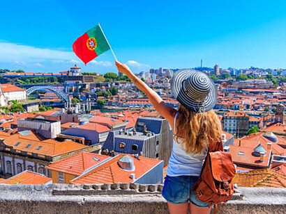 Woman tourist holding portuguese flag in front of panoramic viewpoint of cityscape, Porto, Portugal
