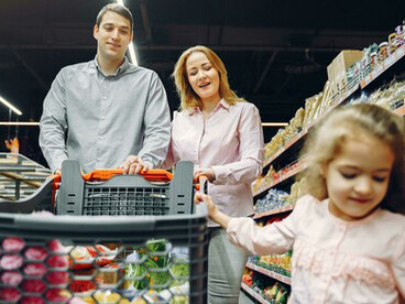 Mother guiding her child through a payment at the supermarket during a family shop