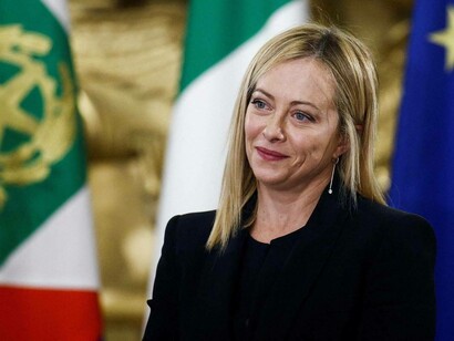 Italian Prime Minister Giorgia Meloni smiles at a question from a reporter
