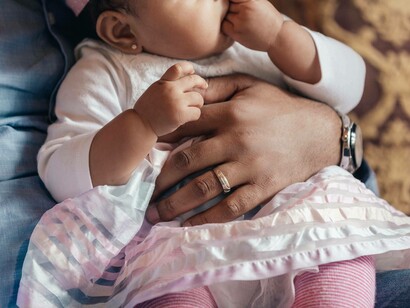 The Godfather has the goddaughter on his lap while she has her hand in her mouth