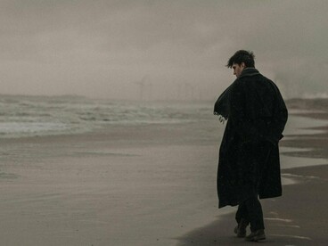 A man walking by the sea alone beneath a dark sky, symbolising the ache of broken connections