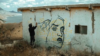 An expressive artist spray-painting the wall of an abandoned building, embodying the spirit of a creative soul