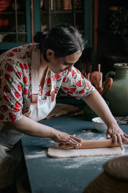 Donna che stende la pasta: "... un tempo, la cucina non era semplicemente un'attività quotidiana: era un rito colmo di significato, un linguaggio silenzioso in cui le donne, con grazia instancabile e sapienza antica, intrecciavano amore e sostanza"