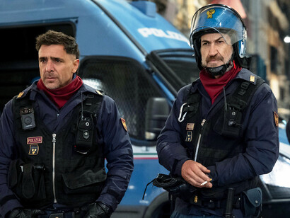 Riot police stand together outside their van, ready for another intense day on the front lines, the weight of their uniforms reflecting the emotional burdens they carry