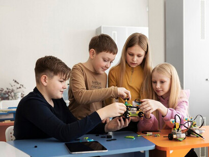 Four children assembling a drone with electronic components, engaging in hands-on learning and technology exploration