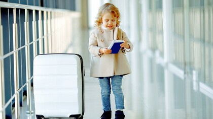 Menina feliz com mala e passaporte no corredor do aeroporto