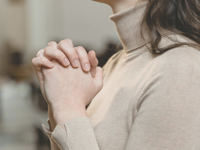 Mujer une sus manos en señal de oración. Que tu voz resuene en mi interior, guiando mis proyectos