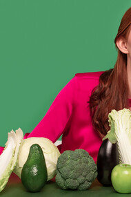 Stunning redhead woman posing with chlorophyll-rich green vegetables for vibrant portrait