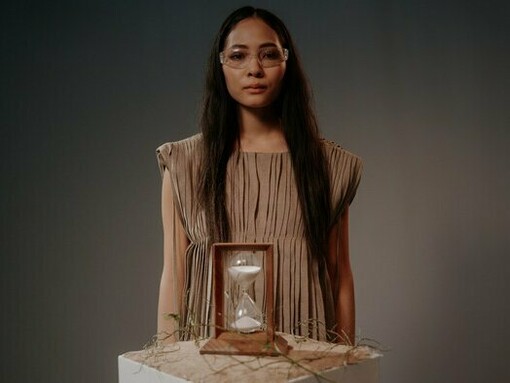 A woman behind an hourglass, mirroring the idea that aging is no longer an unstoppable countdown