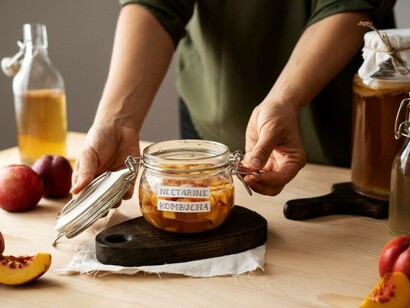 A woman gets ready to serve nectarine kombucha, carefully labeling the jar