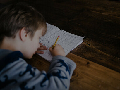 Niño escribiendo en un cuaderno. En el mundo de la razón universal se anulan los conflictos globales, sociales, y personales