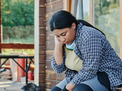 A woman in a yellow hard hat and plaid shirt at work, focused on earning a living