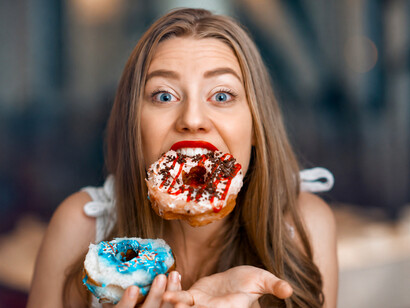 Woman gazing longingly at freshly baked donuts, symbolizing sweet cravings and temptation