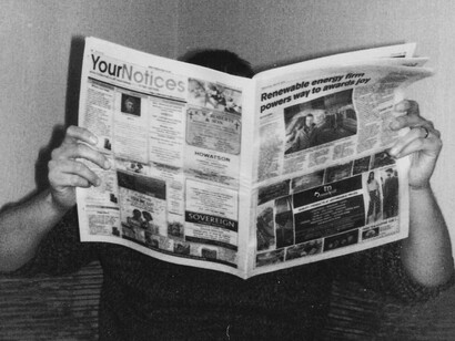 Un lector absorbido por la lectura de su periódico, simbolizando el poder de la censura y la manipulación de los medios