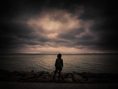 Mujer contempla la templanza del mar antes de la tormenta. El cielo tiene nubes con memoria y sin agua
