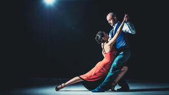 A couple tangoing beneath the spotlight