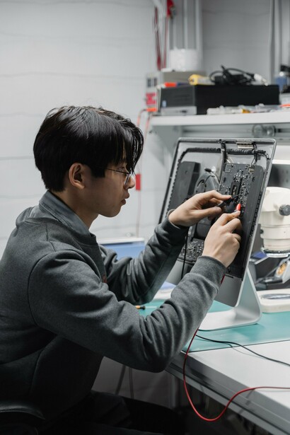 A technician carefully repairing an electronic device at a workbench, representing the importance of repairing and extending the lifespan of electronics to reduce e-waste