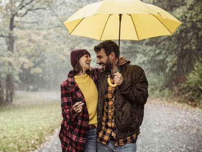 A happy couple walks closely beneath an umbrella through a misty forest on a beautiful autumn day