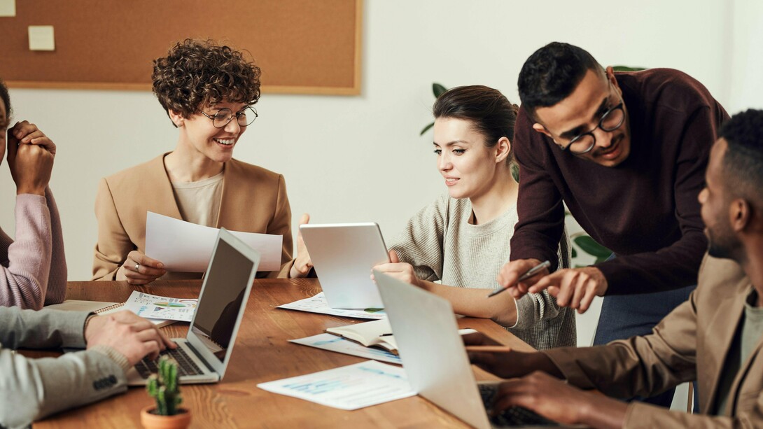Employees gathered around a table, working together with visible energy, highlighting the motivation that comes from having a stake in the outcome