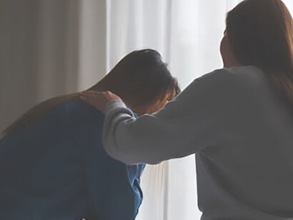 A supportive sister consoles and embraces a woman in the bedroom, offering comfort and encouragement after a nightmare