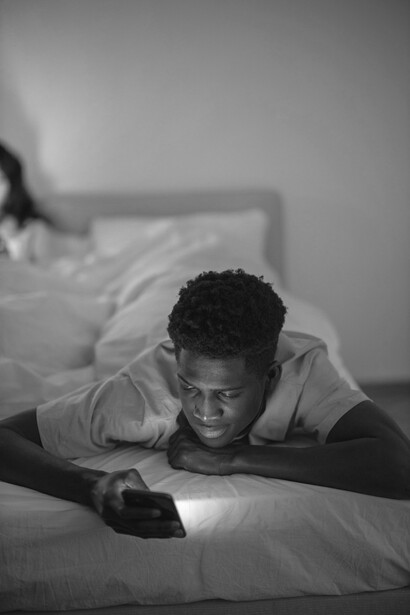 A couple in bed absorbed in their phones, showing how digital distractions create emotional distance and loneliness