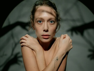 A woman holding herself in darkness, representing the emotional weight of constant self-comparison