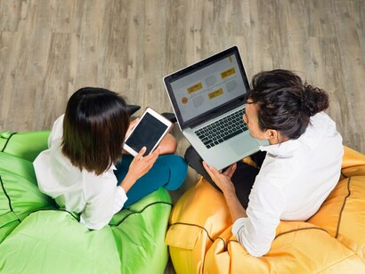 Two business people engage in teamwork with a tablet and laptop, focusing on networking platforms, global connectivity, group guidelines, and enhancing social media interaction