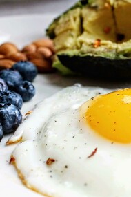 A fresh composition of an egg, blueberries, nuts, and avocado — a wholesome Paleo-inspired breakfast