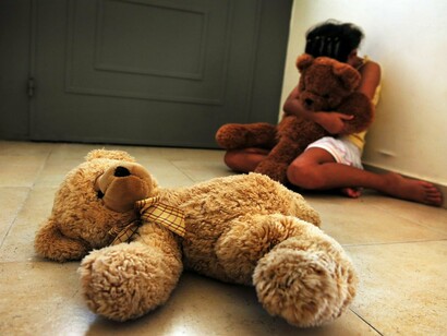 Una niña esconde su cara con miedo tras un muñeco de peluche